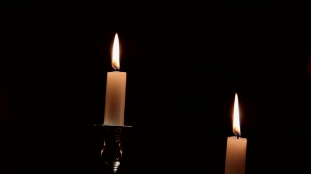Αναμμένα κεριά σε ασημένιο κηροπήγιο στο σκοτεινό μπουκέτο του φόντου μαραμένα τριαντάφυλλα — Αρχείο Βίντεο