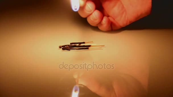 Человек зажигает спичку в темноте и горит с отражением на поверхности стекла — стоковое видео