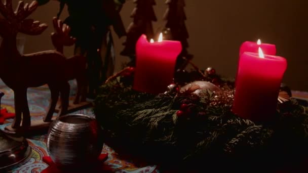 Instalación de Navidad con velas decorativas rojas ardientes y corona de abetos en la mesa — Vídeo de stock