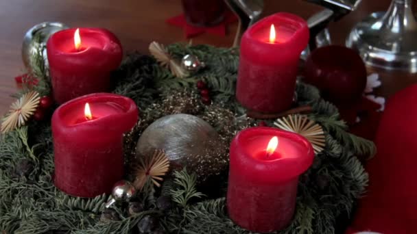 Instalação de Natal com velas decorativas em chamas vermelhas e grinalda de fir- árvores na mesa de madeira marrom — Vídeo de Stock