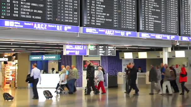 Passagiere in einer der Hallen des Frankfurter Flughafens mit Flugplanbildschirmen — Stockvideo