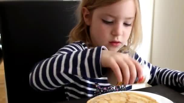 Девочка в полосатом платье сидит за столом и думает — стоковое видео
