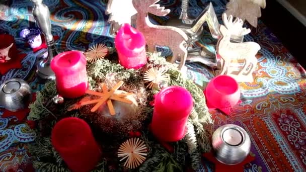 Decoración de Navidad con velas rojas y corona de los primeros árboles en la mesa — Vídeo de stock