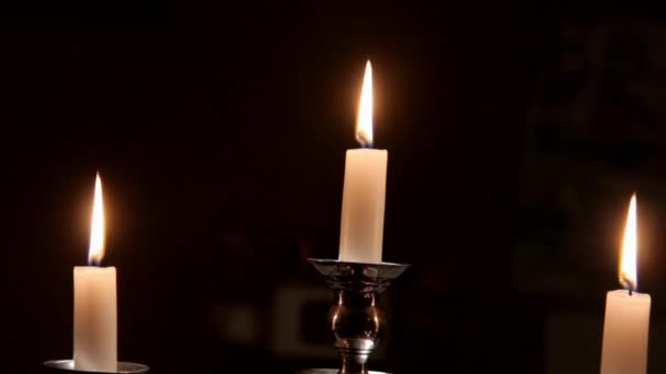 Zblízka pohled z hořící svíčky v stříbrný svícen na tmavém pozadí