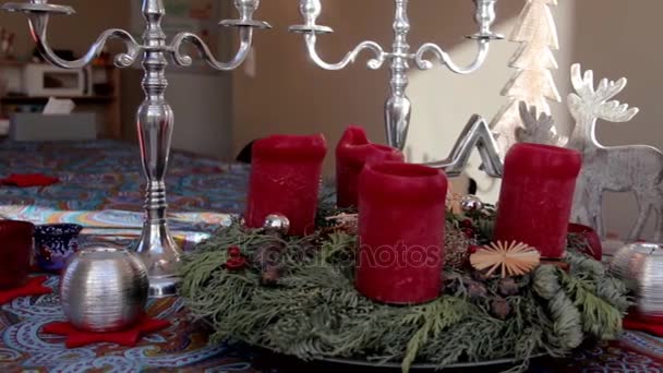 Decoración de Navidad con velas rojas y corona de los primeros árboles en la mesa — Vídeo de stock