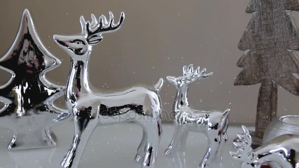 Vánoční dekorace hračky jeleny, vánoční stromky a dekorativní svíčka stojící na bílé příborníku
