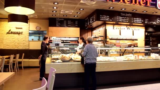 Pasajeros cerca de un pequeño café en uno de los salones del aeropuerto internacional de Frankfurt — Vídeos de Stock