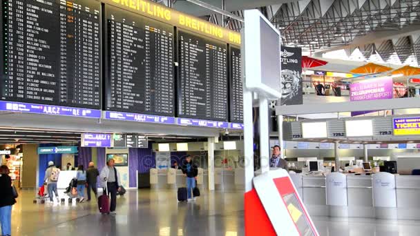 Passagiere in einer der Hallen des Frankfurter Flughafens mit Flugplanbildschirmen. Terminal c — Stockvideo
