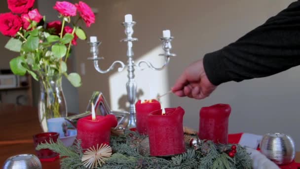 Пожилой человек зажигает красные декоративные свечи на деревянном столе — стоковое видео
