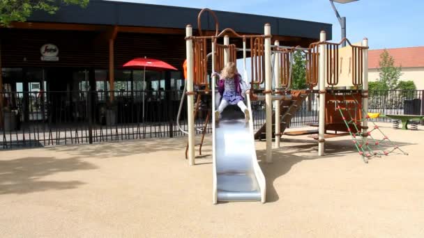 Kleines süßes blondes Mädchen fährt von einer Achterbahn auf einem Kinderspielplatz — Stockvideo