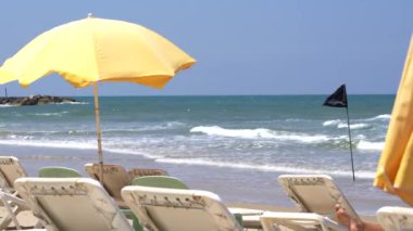 Plaj ile sarı şemsiye, plastik şezlong mavi dalgalar deniz ve gökyüzü arka plan