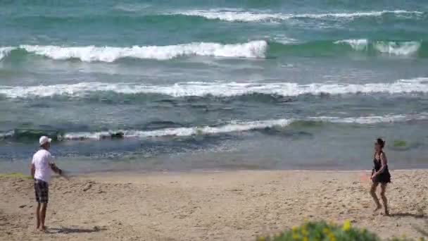 若いカップルの青い海を背景に砂浜でテニス — ストック動画