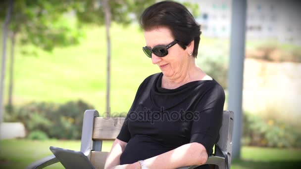 Babička, pomocí Tablet v parku — Stock video