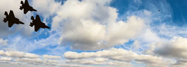 Siluetas de tres aviones F-35 contra el cielo azul y las nubes blancas — Foto de Stock