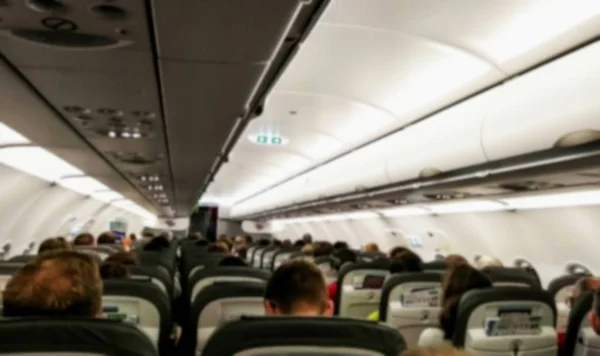 Interior de un avión comercial moderno con pasajeros en sus asientos esperando despegar . — Foto de Stock