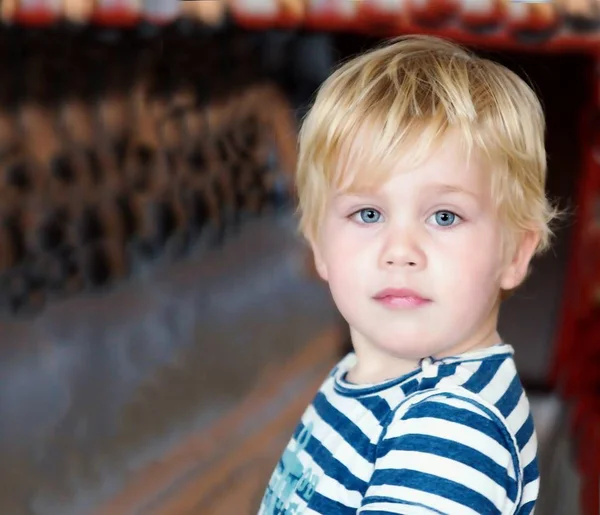 Zweijähriger blonder Junge mit blauen Augen in einem gestreiften T-Shirt auf abstraktem Hintergrund — Stockfoto