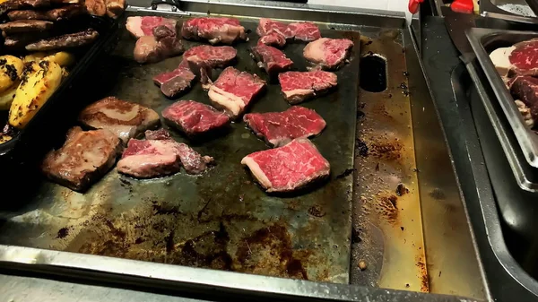 電気ストーブの上にステーキを準備します ホテルのレストランで大きなベーキングシートに揚げ牛肉の肉の作品を食欲をそそる 選択的焦点 — ストック写真