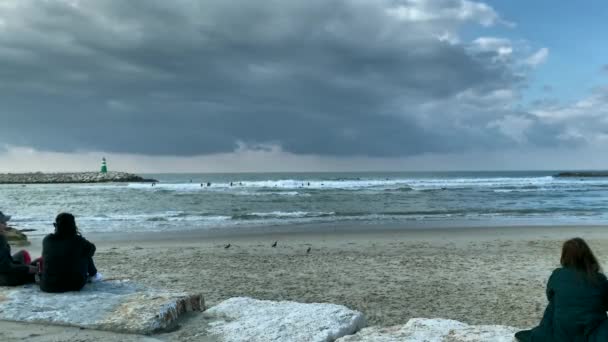 Tel Aviv Israel January 2020 背景にサーファーと嵐の海の海岸に若い女性 — ストック動画