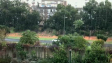 Büyük Akdeniz kasabasında bazen yoğun tropikal yağmur dolu yağar. Beşinci katın açık penceresinden bak. 4 bin. Bulanık görünüm