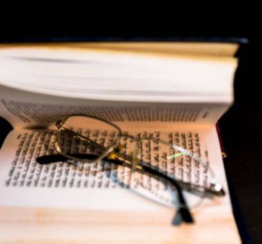 Talmud Torah Tanakh 'ın kara arka plan kitabını gözlüklerle aç. Seçici odaklanma. Bulanık görünüm