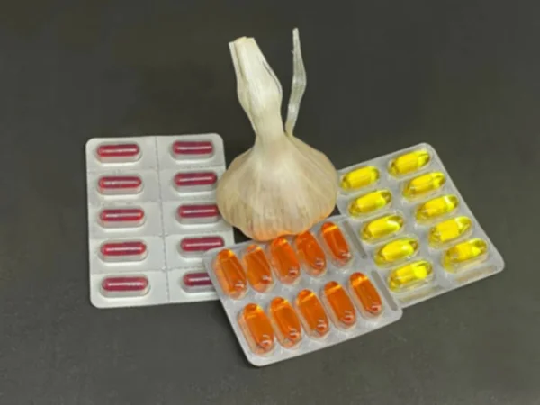 コピースペースが付いている暗い背景のブリスターパックの新鮮なニンニク 丸薬およびビタミン 医薬品のコンセプト 選択的フォーカス ぼやけた景色 — ストック写真