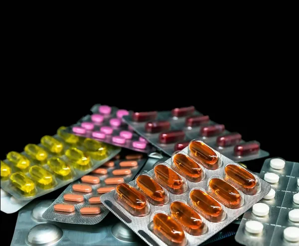 コピースペースが付いている暗い背景のブリスターパックの丸薬及びビタミンの山 医薬品のコンセプト 選択的焦点 — ストック写真