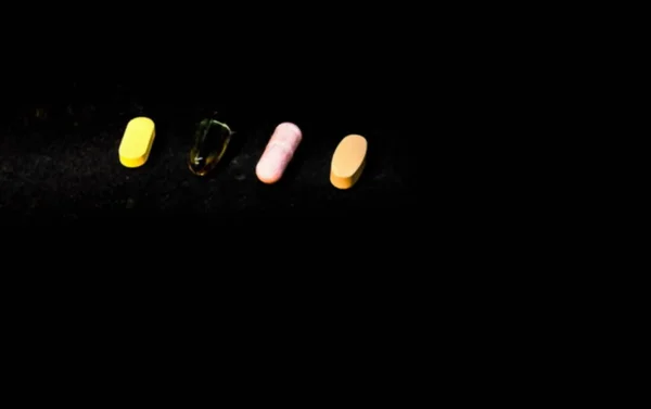 Quatro Comprimidos Fundo Escuro Conceito Farmacêutico Foco Seletivo Vista Turva — Fotografia de Stock