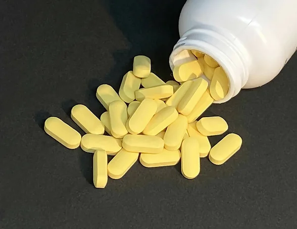 Sarı Vitamini Tabletleri Serpilmiş Arka Planda Beyaz Hap Şişesi Var — Stok fotoğraf