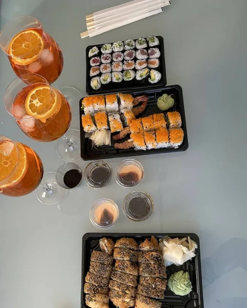 在餐厅或酒吧 寿司盘的桌子上摆放着三种不同的寿司菜单的Aperol Spritz葡萄酒杯的不同寻常的原始顶部视图 有选择的重点 — 图库照片