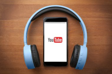 Ön tarafı gösteren bir akıllı telefonun etrafında bir çift mavi kulaklık. 