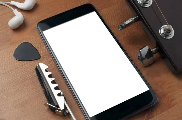 Černá obrazovka smartphone na dřevěném stole vedle kytary, některé — Stock fotografie