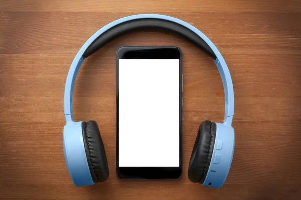 Oran 'daki boş ekran akıllı telefonun etrafında bir çift mavi kulaklık.