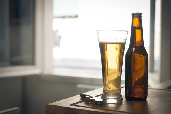 Láhev a sklenici piva a vývrtku na dřevěném povrchu. — Stock fotografie