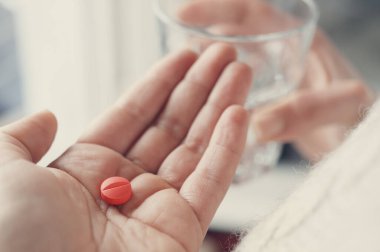 Bir bardak suyun yardımıyla hap almak üzere olan bir kadın.