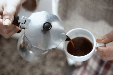 Sabahları kahvaltıda kahve dolduran bir kadın.