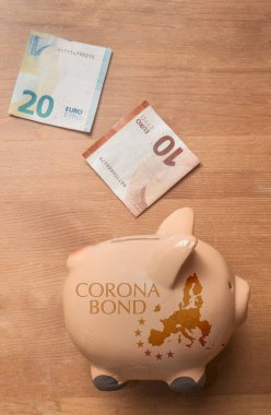 Coronabond konsepti: Avrupa haritalı bir domuz kumbarası ve tahtadan bir masanın üzerine basılmış Coronabond metni.. 