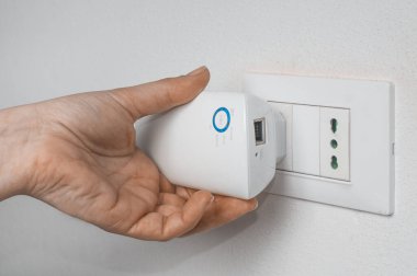 Kadın, duvar prizine kablosuz ağ vericisi takıyor.