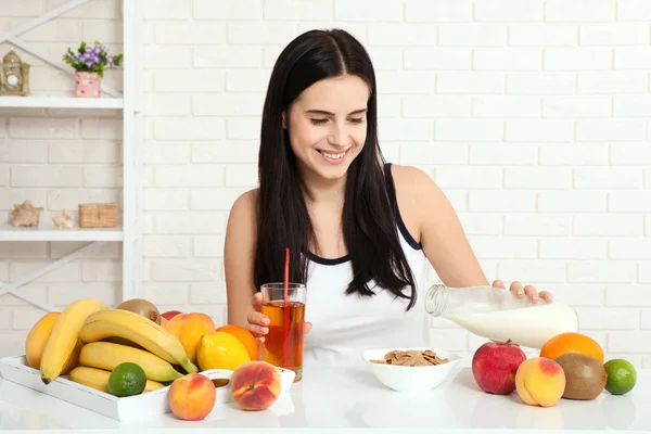 Schöne Frauen mit reiner Haut im Gesicht sitzen an einem Tisch und frühstücken. Asiatin, die sich beim Frühstück gesund ernährt. Obst, Getreide und Milch. — Stockfoto