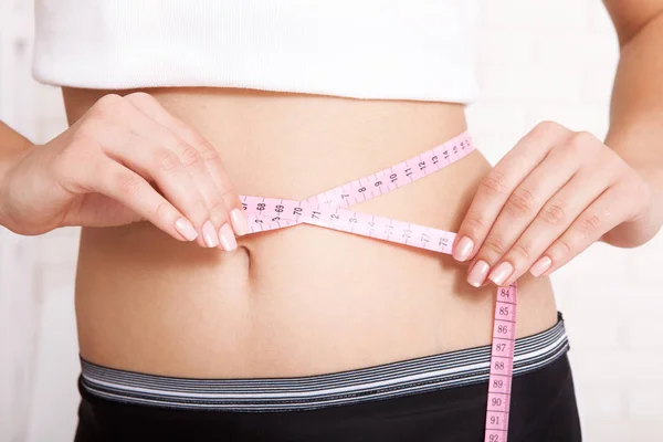 Sport, fitness and diet concept - closeup of trained belly with measuring tape — Stock Photo, Image