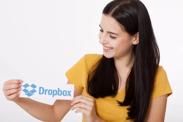 KIEV, UCRANIA - 22 de agosto de 2016: Manos de mujer con el logotipo de Dropbox impreso en papel sobre fondo blanco. Almacenamiento en la nube de Dropbox, que permite a los usuarios almacenar sus datos en servidores en la nube . —  Fotos de Stock