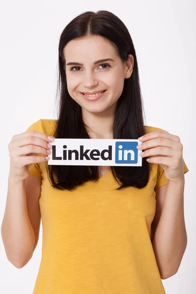 KIEV, UCRAINA - 22 agosto 2016: Mani femminili con il logo Linkedin stampato su carta su sfondo bianco. Linkedin è un servizio di social networking aziendale . — Foto Stock