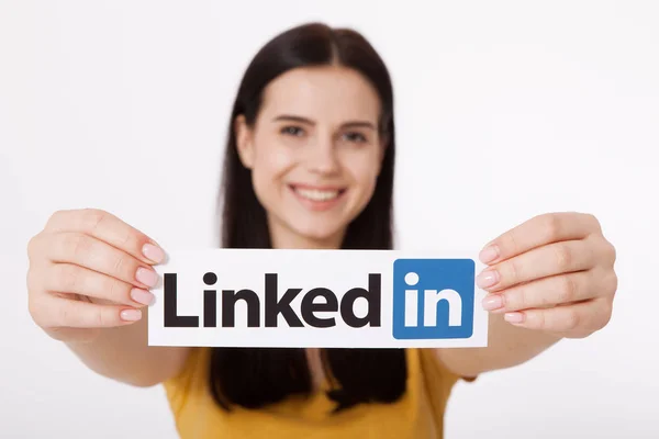 KIEV, UCRAINA - 22 agosto 2016: Mani femminili con il logo Linkedin stampato su carta su sfondo bianco. Linkedin è un servizio di social networking aziendale . — Foto Stock