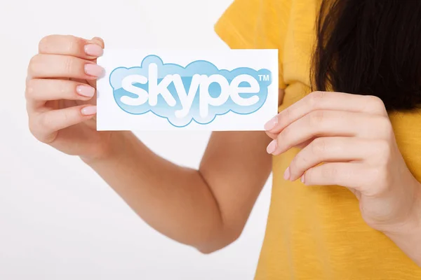 Kiev, Oekraïne - 22 augustus 2016: Vrouw handen met Skype logo gedrukt op papier op een grijze achtergrond. Skype is een telecommunicatie applicatiesoftware ontwikkeld door Microsoft. — Stockfoto