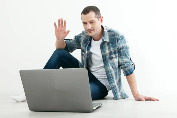 Молодой человек разговаривает друг с другом через онлайн видео чат. Красивый человек, использующий ноутбук для бизнеса и развлечений — стоковое фото
