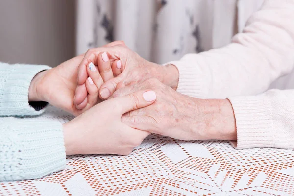 Old and young holding hands at home, closeup — Stock Photo, Image