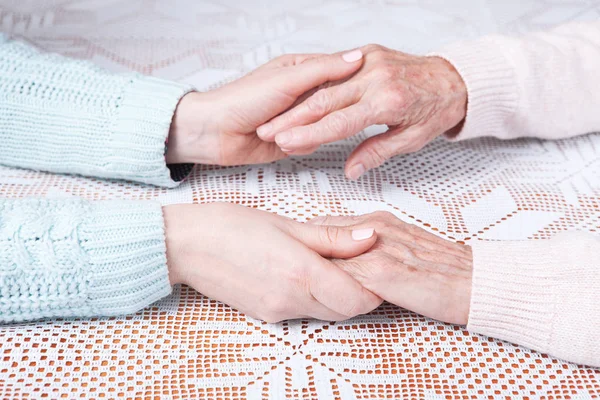 Mulher idosa com seu cuidador em casa. De mãos dadas, horizontalmente vista superior close-up . — Fotografia de Stock