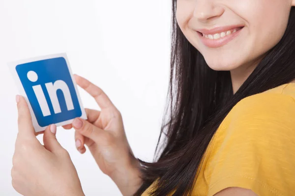 KIEV, UCRAINA - 22 agosto 2016: Mani femminili con il simbolo Linkedin stampato su carta su sfondo bianco. Linkedin è un servizio di social networking aziendale . — Foto Stock