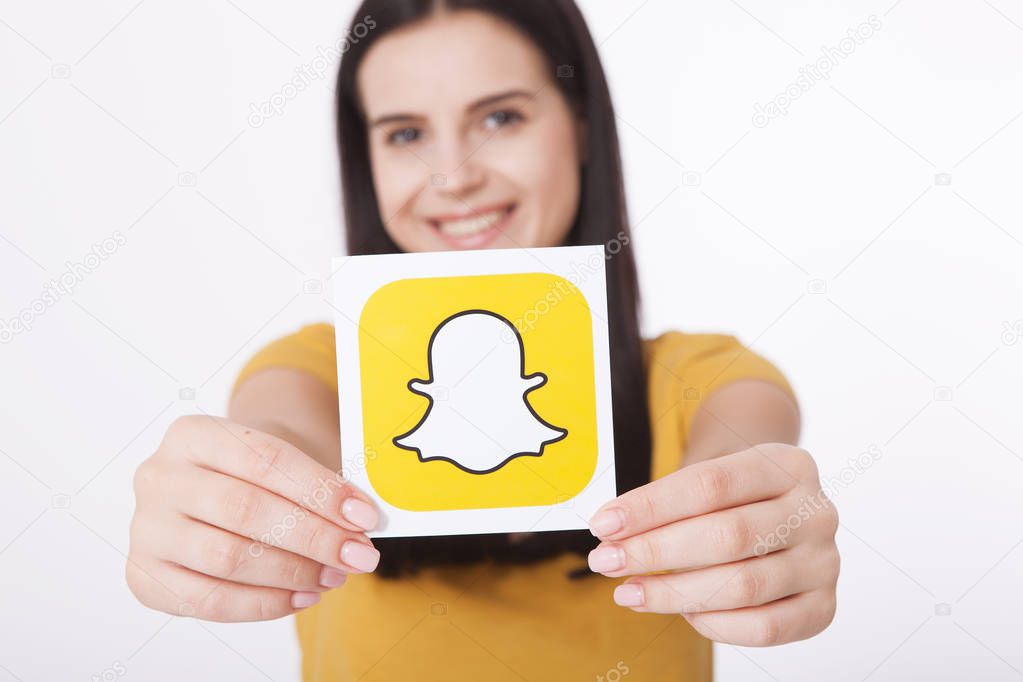 Kiev, Ukraine - August 22, 2016:Woman Hands holding Snapchat logo icon printed on paper. Snapchat is a popular social media application for sharing messages, images and videos