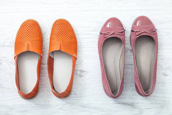 Flat lekmanna fashion som: färgad tofflor skor på vit trä bakgrund. Ovanifrån. — Stockfoto