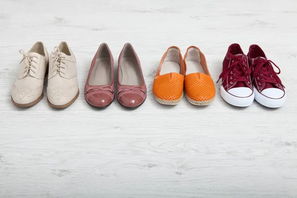 Flat lay fashion set: colored slippers shoes on white wooden background. Top view. — Stock Photo, Image